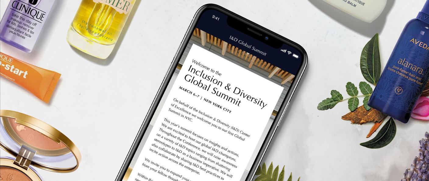 Smartphone displaying Inclusion & Diversity Global Summit page surrounded by cosmetics and plant accents