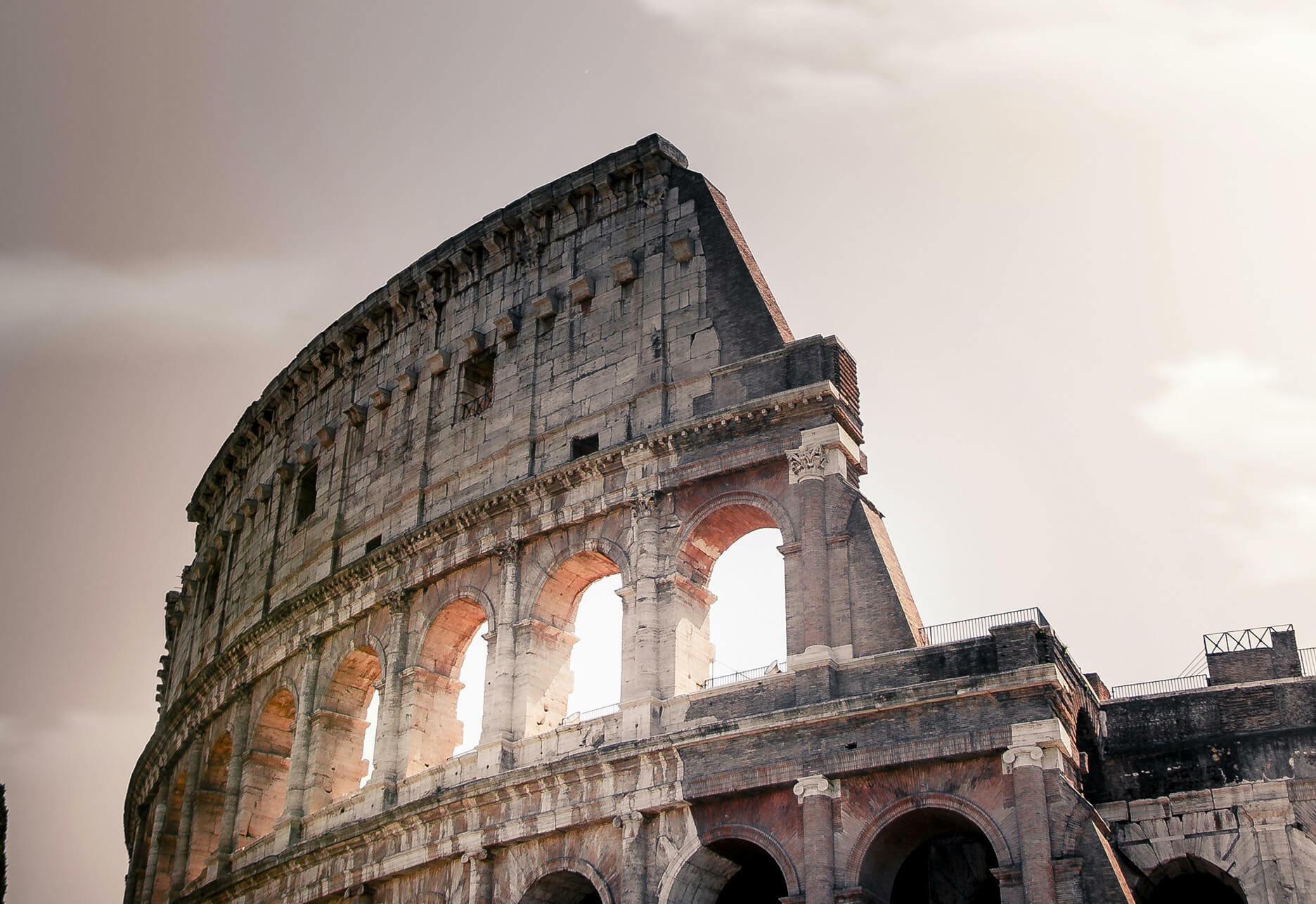 Low-angle view of the Colosseum with arched stone walls