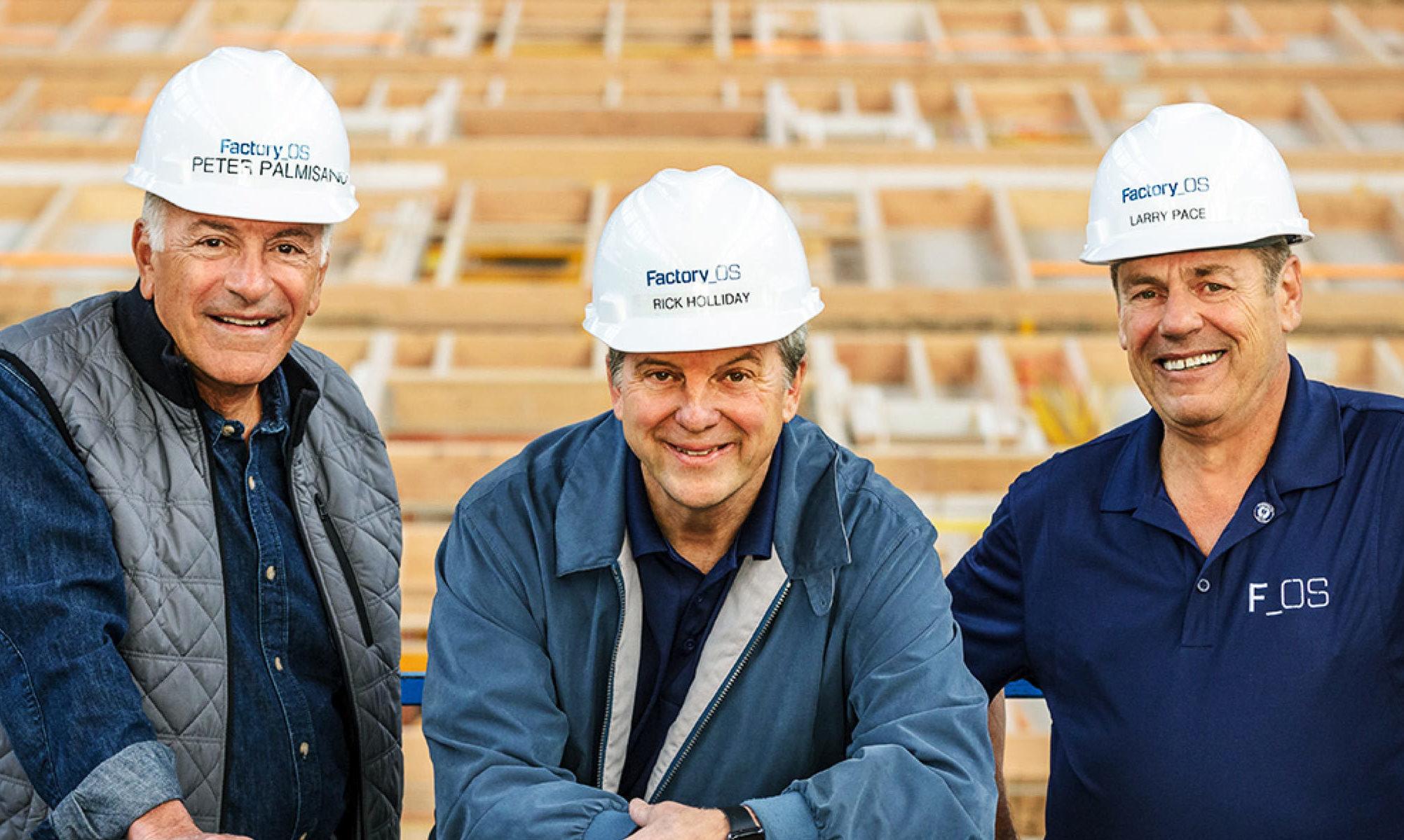 Three construction workers wearing hard hats seated at a building site