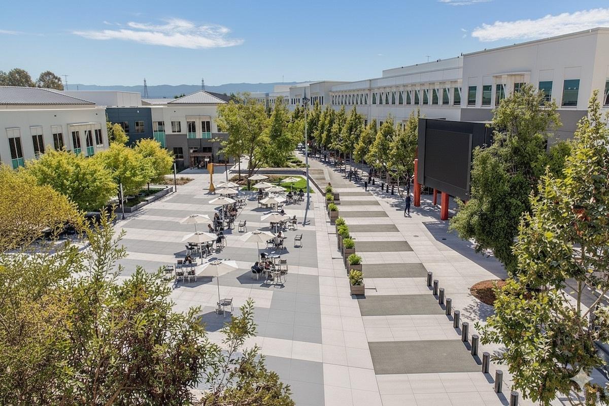 Tree-lined corporate campus courtyard with tables and walkways