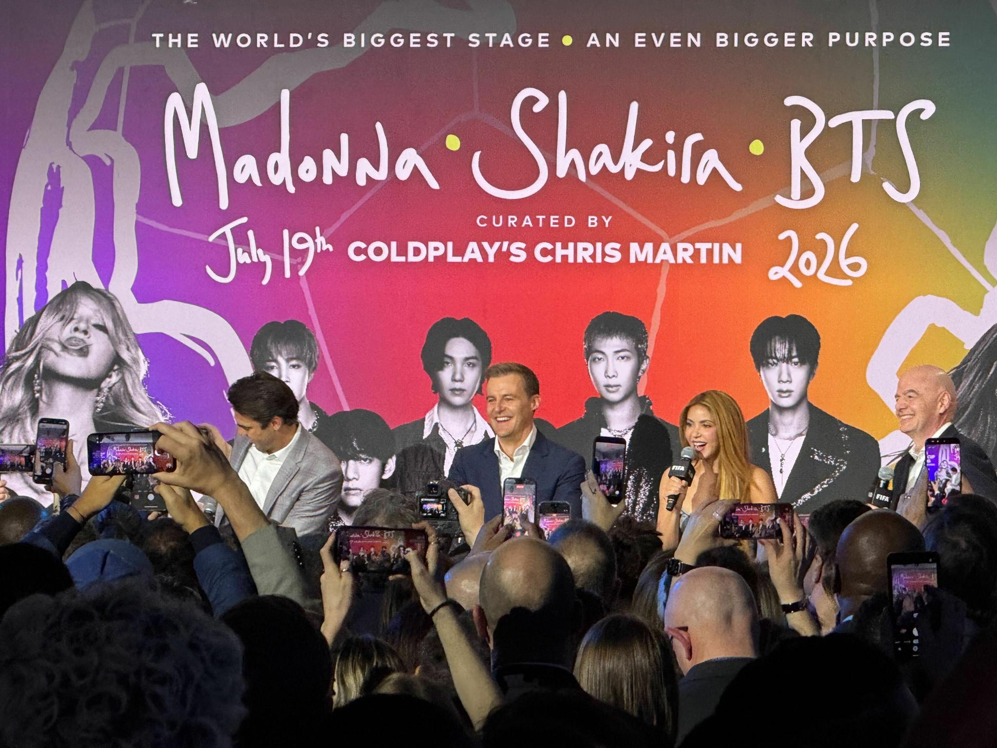 Crowd at event with banner mentioning Madonna, Shakira, BTS, and Coldplay's Chris Martin