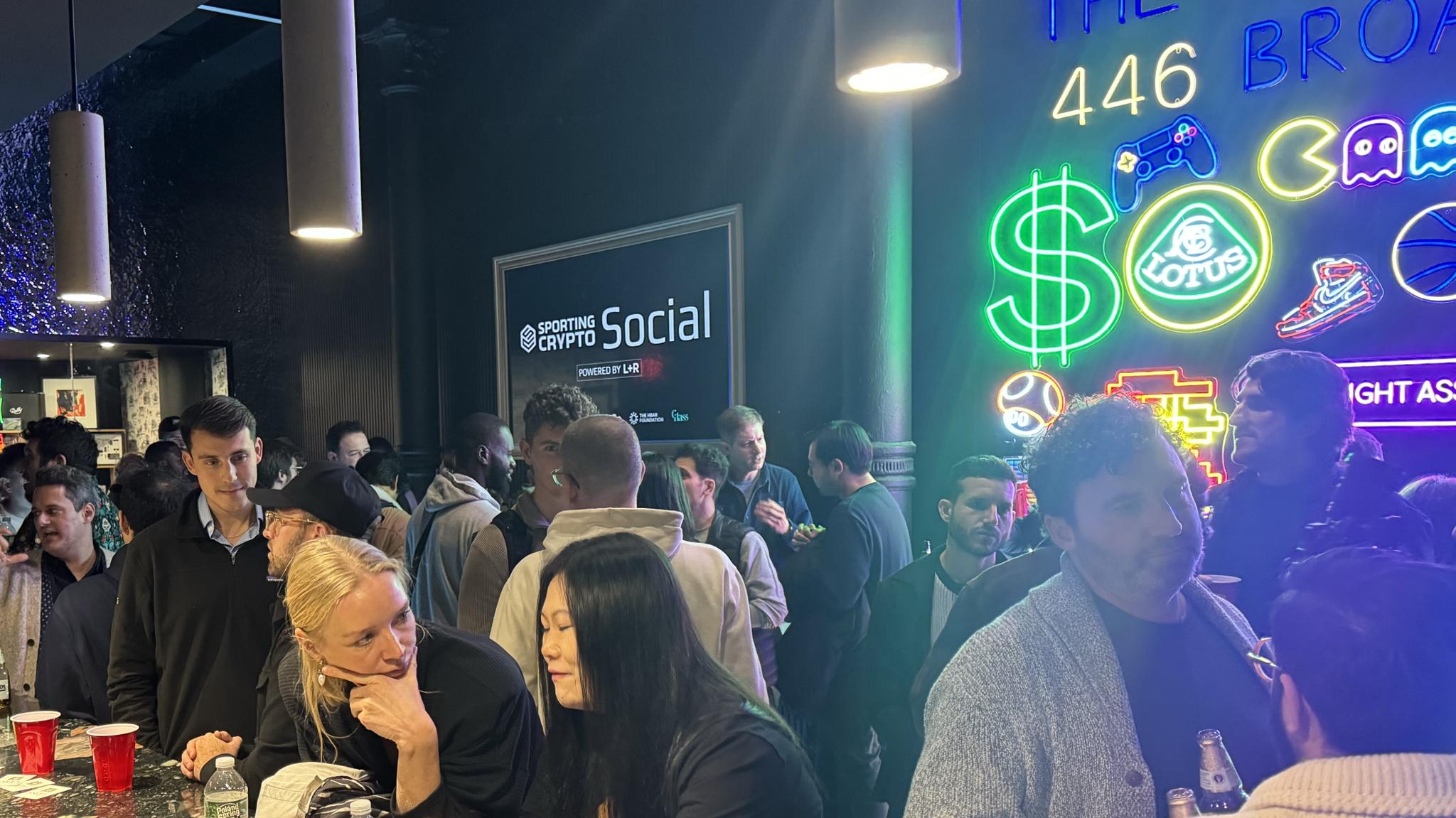 Networking event crowd beside bright neon arcade-style signs
