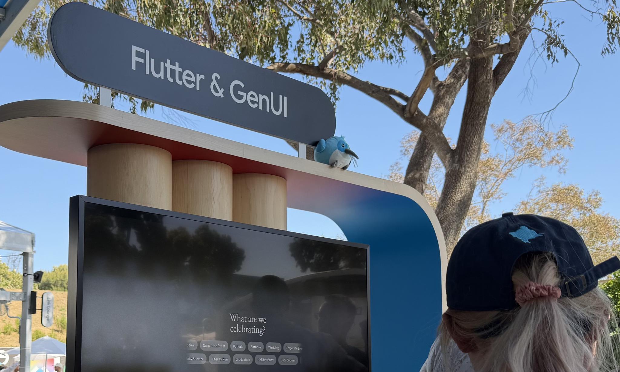 Outdoor Flutter and Gemini booth sign with a person standing nearby