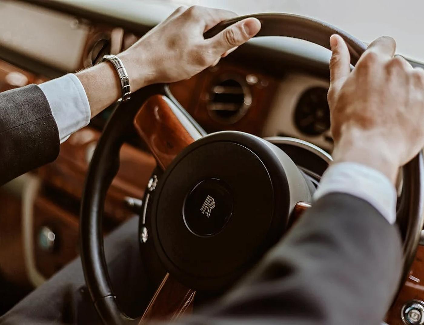 Hands on a Rolls-Royce steering wheel inside a luxury car