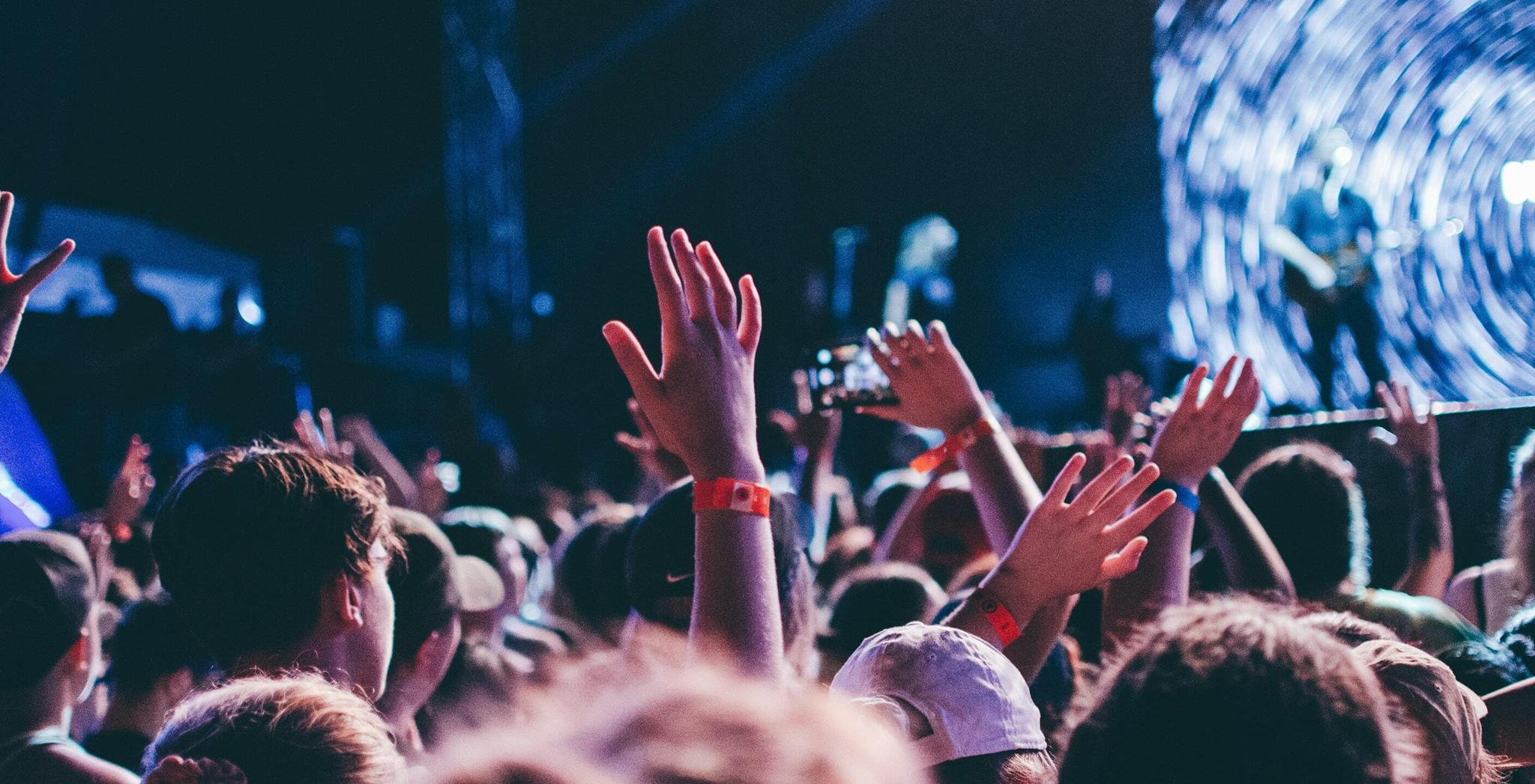 Music Entertainment 2 min Concert crowd with raised hands facing a bright stage