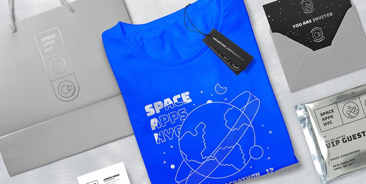 Blue "Space Pops NY" T-shirt with branded packaging and printed materials on a table