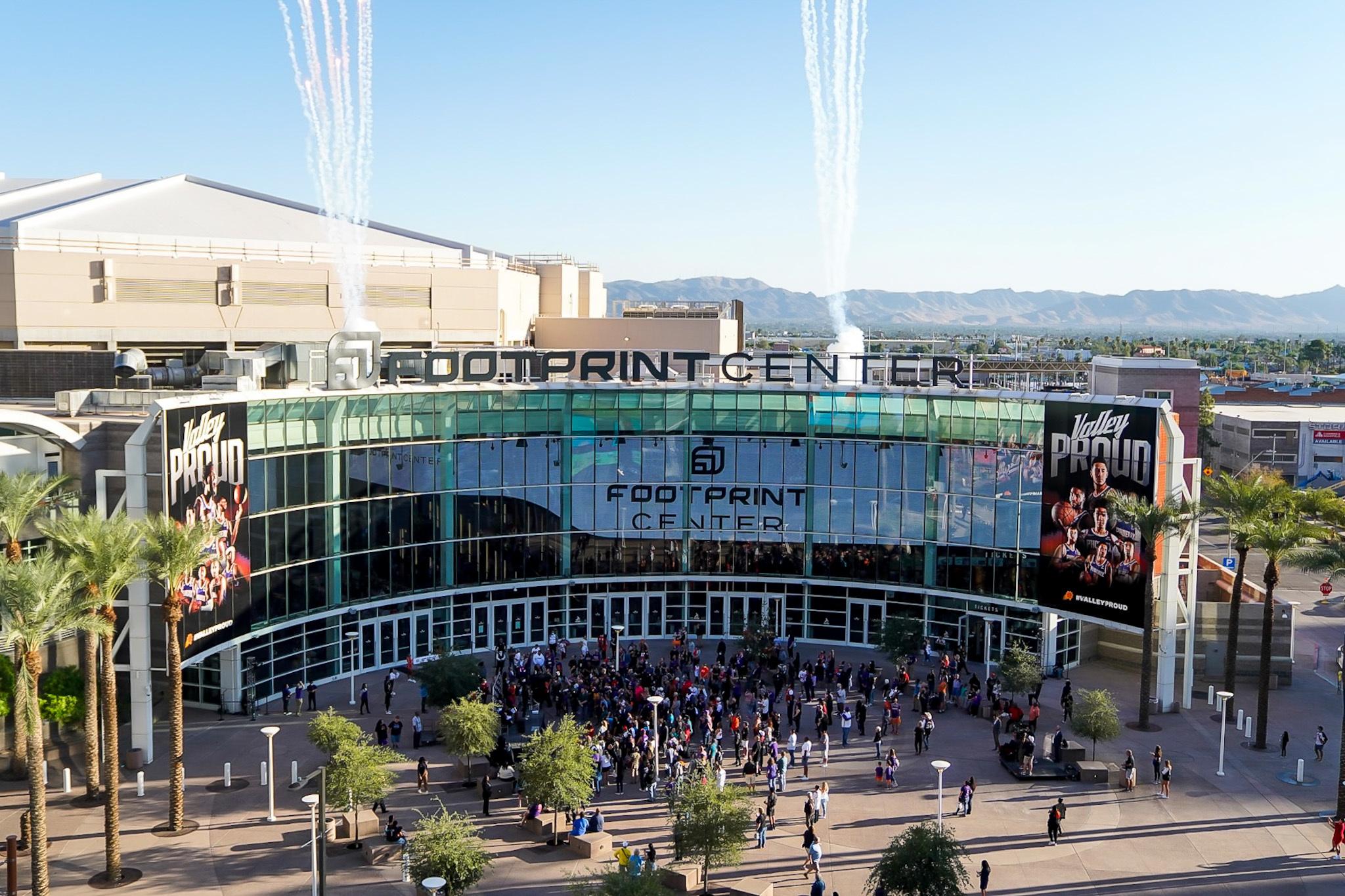 Footprint Center exterior with crowds and fireworks in daylight