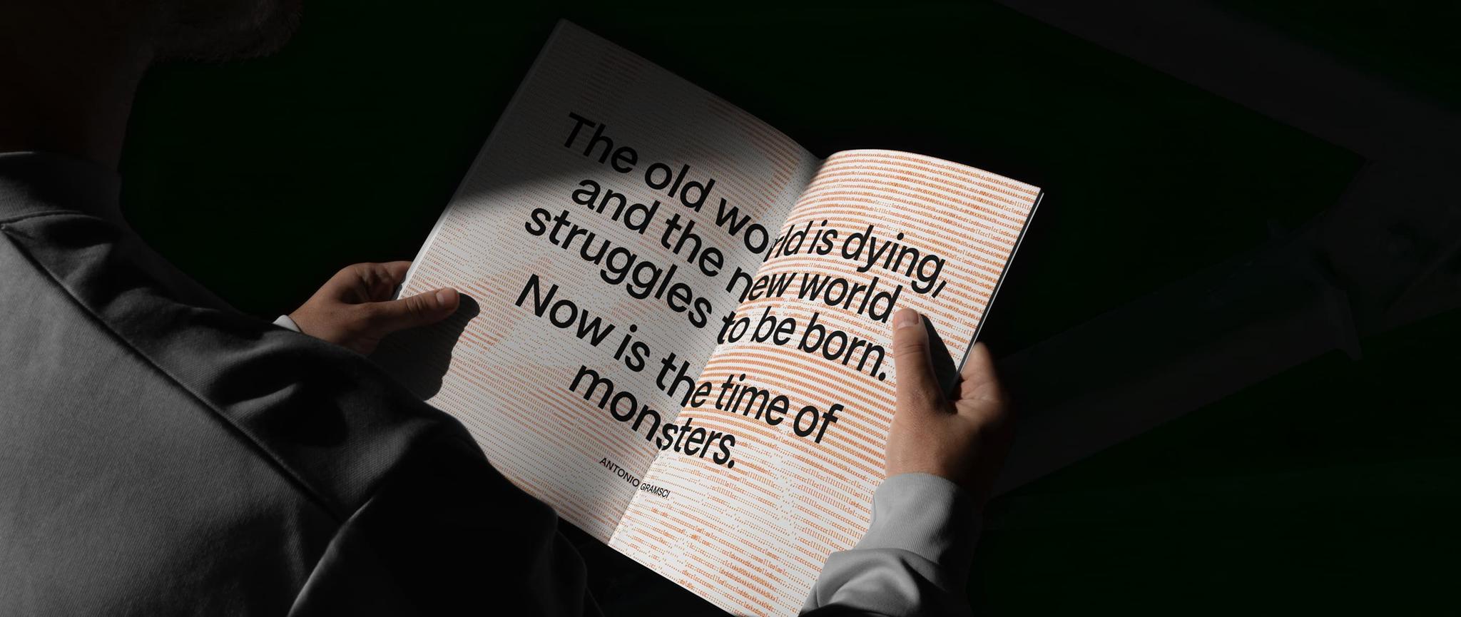 Hands holding an open book with a large quote about the old world dying