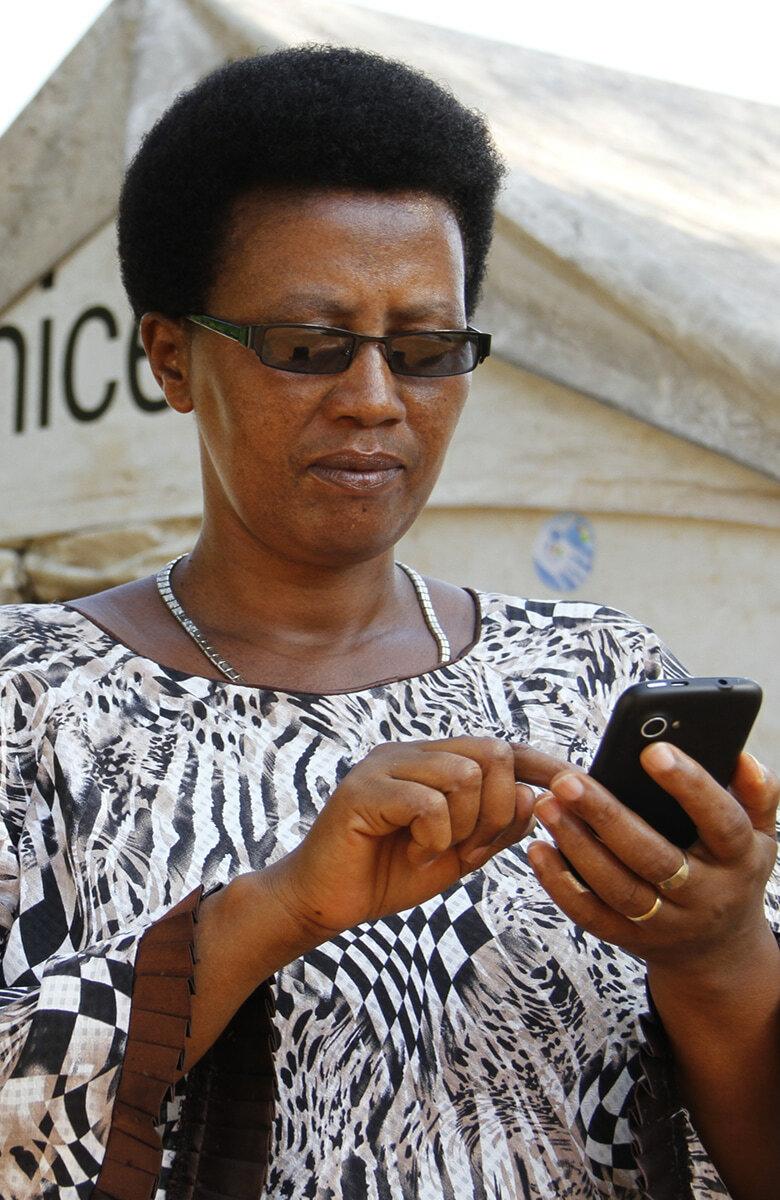 Close-up of a woman using a phone in front of a UNICEF tent.