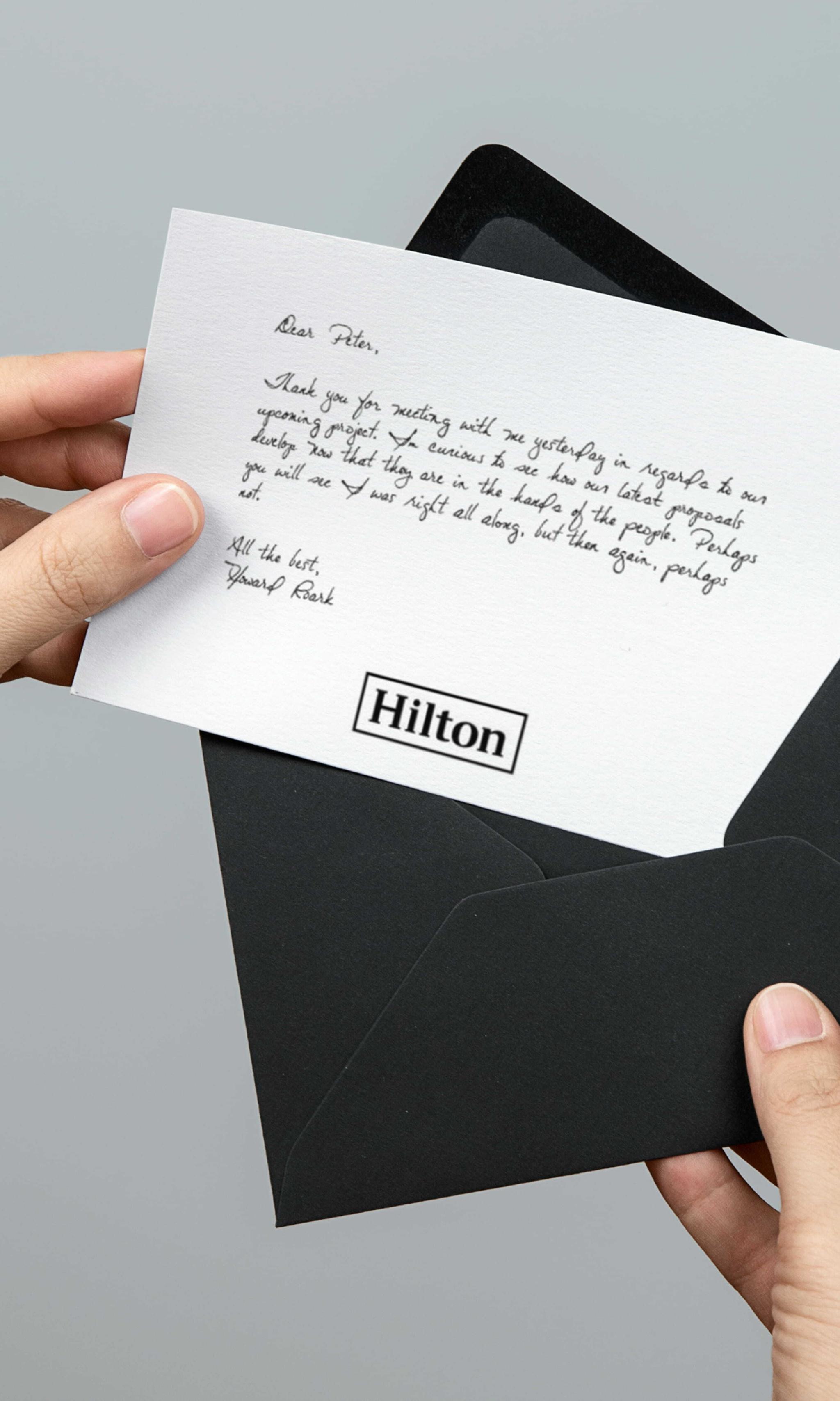 Hilton-branded handwritten note being pulled from a black envelope
