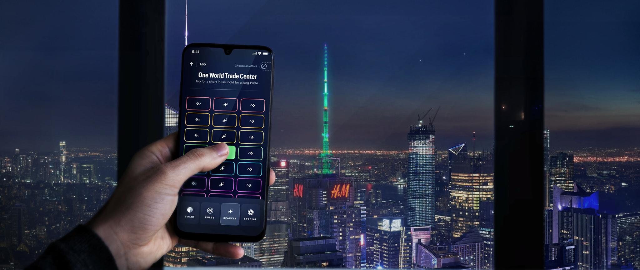 Hand holding a smartphone lighting control app against a nighttime New York skyline