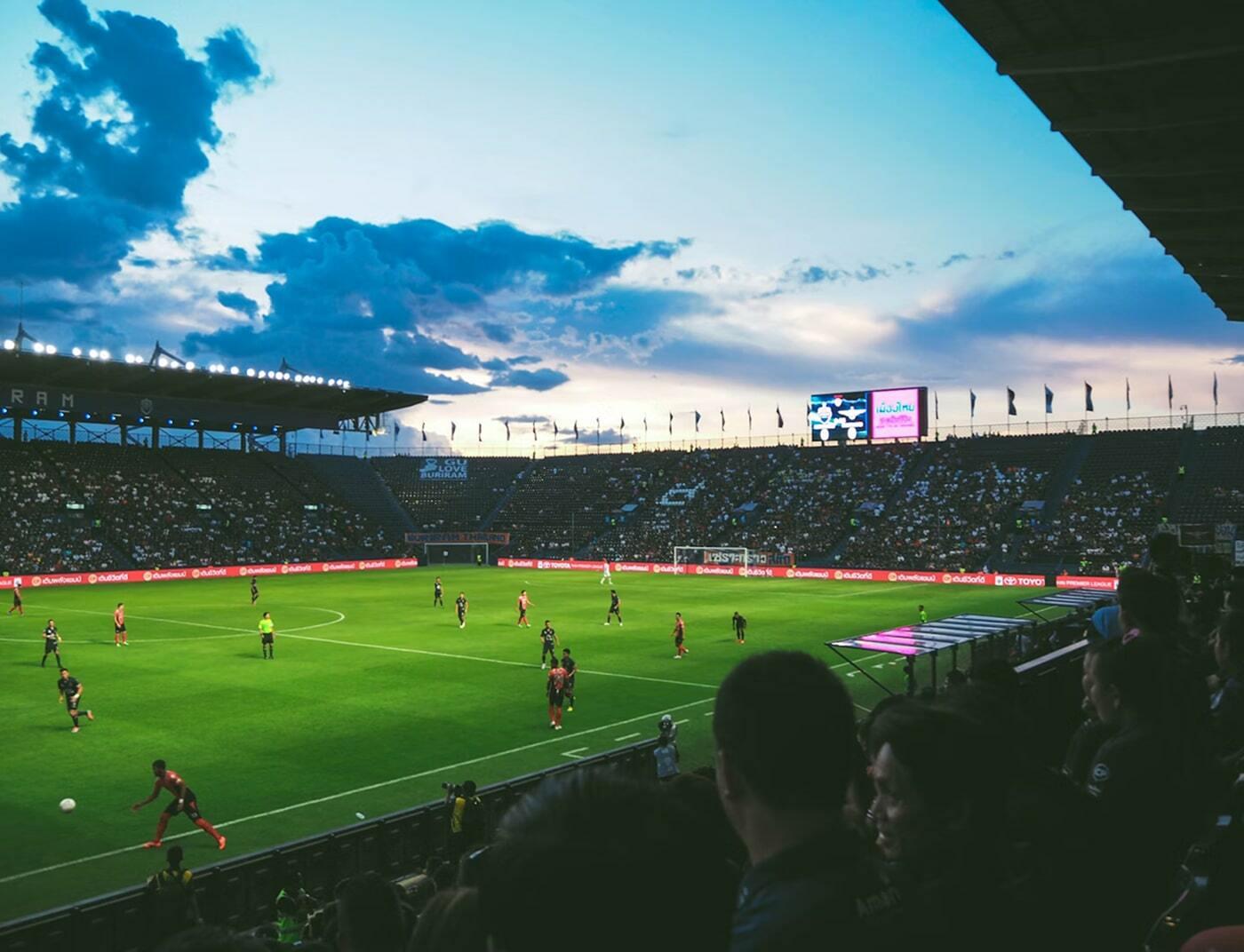 Soccer match in a stadium at dusk with fans in the stands