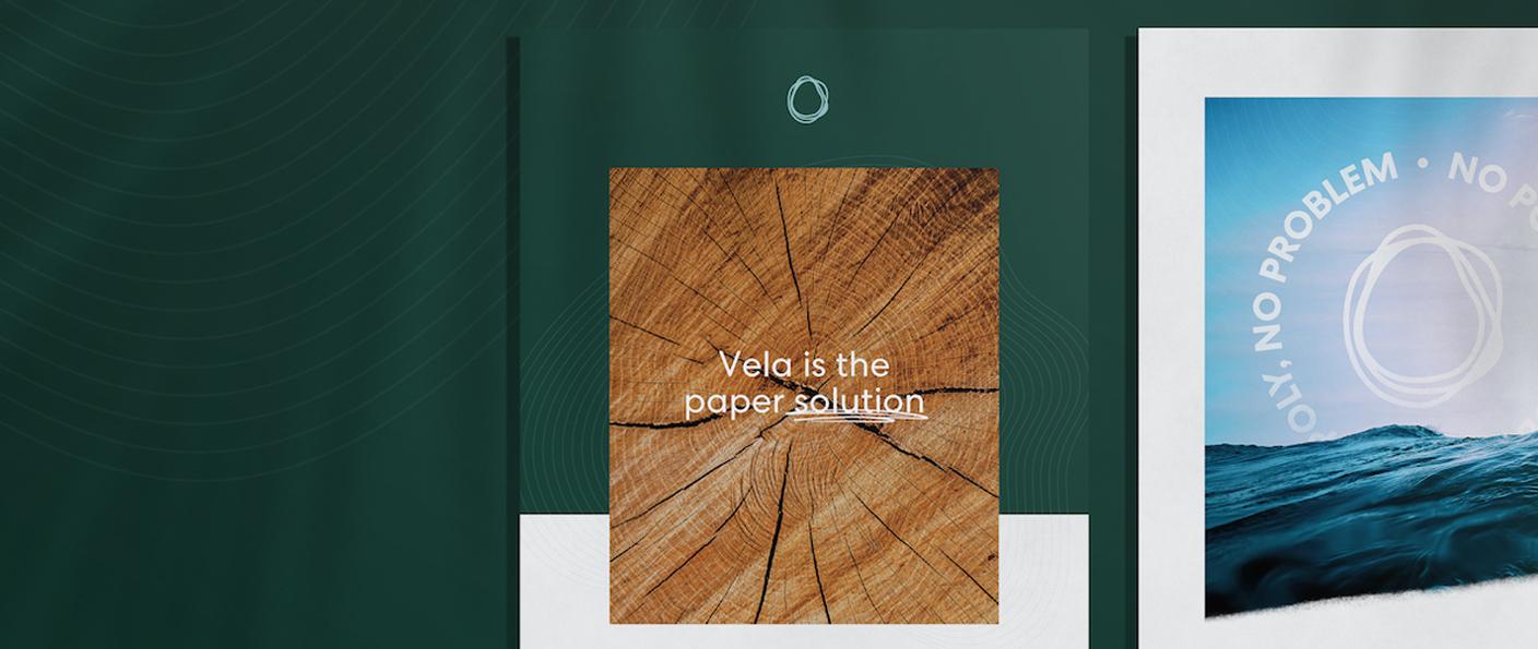 Green paper packaging mockup with wood grain insert reading "Vela is the paper solution"