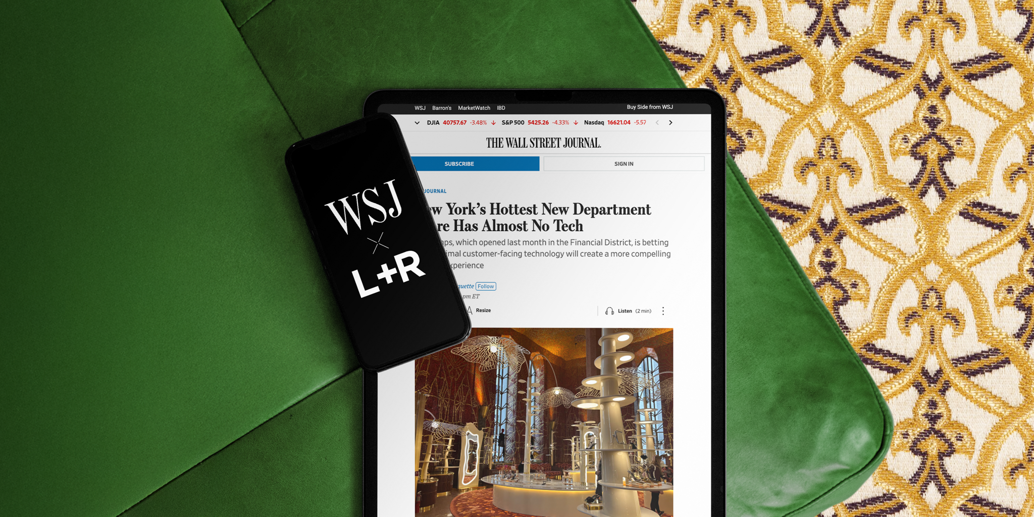 Tablet showing a Wall Street Journal article beside a WSJ L+R phone case