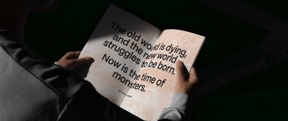 Rainbow Paper Desktop Cover Hands holding an open book with a large quote about the old world dying