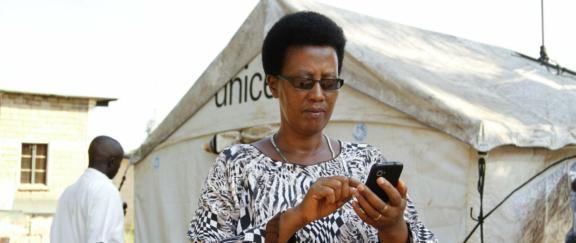 Rapid Pro Hero Desktop Woman using a phone in front of a UNICEF tent.