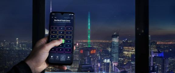 Spireworks2 0 D Cover Hand holding a smartphone lighting control app against a nighttime New York skyline
