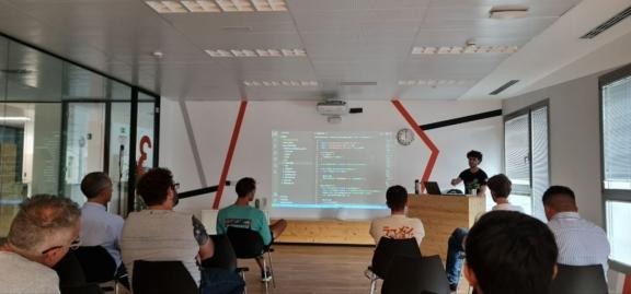 Audience watches a presenter project code in a conference room