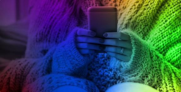 Hands holding a smartphone while wearing a chunky knit sweater