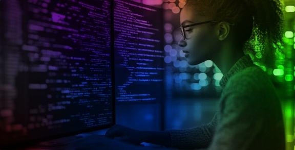 Person working at computer monitors filled with code