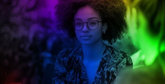 Woman with glasses lit by purple, blue, and green neon colors
