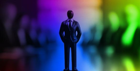Small suited figurine standing before blurred colorful shapes
