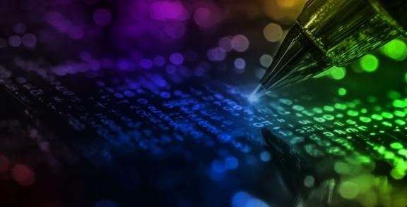 Pen tip touching glowing binary digits on a dark surface