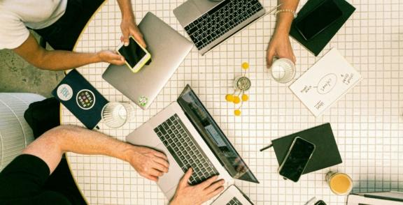 Startups Ventures 2 min Overhead view of laptops, phones, notebooks, and drinks on a table