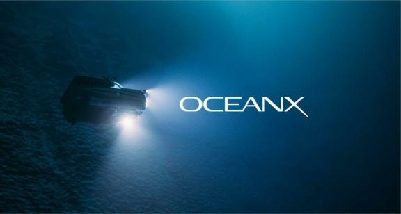 OceanX logo over an underwater vehicle with lights in deep water