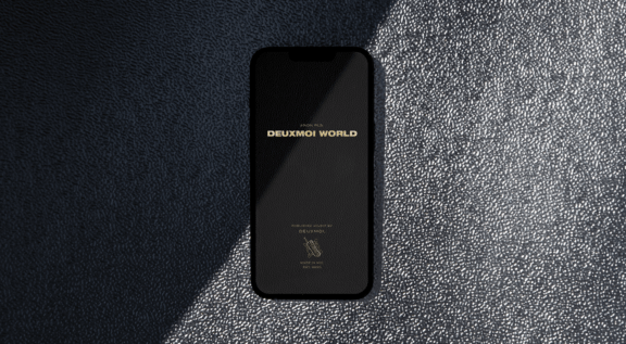 Header Phone with Deuxmoi World splash screen on textured black surface