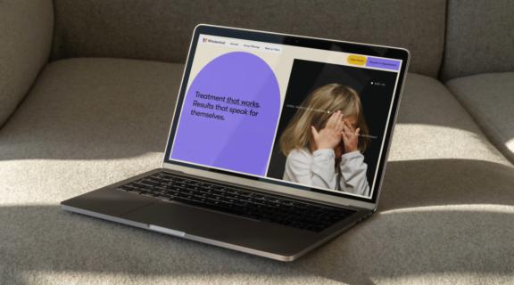 Laptop on a couch showing the WholeMind Psychology website