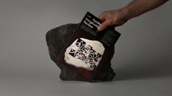 Hand holding a black card above a packaged product on a rock