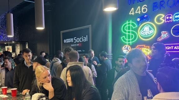 Networking event crowd beside bright neon arcade-style signs