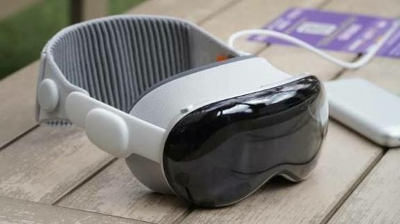 Mixed reality headset resting on a wooden table beside accessories