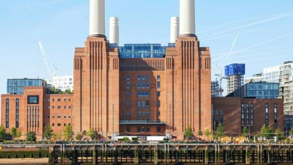 Large brick power station building with tall white chimneys by the river