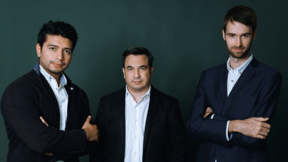 Three businesspeople posing against a dark green background