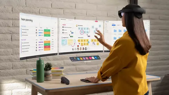 Person wearing a headset gestures at floating virtual work screens