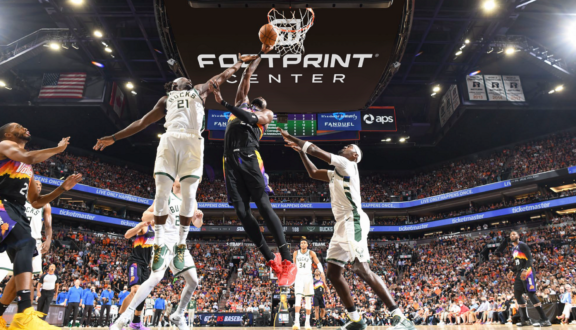 Basketball players jump for a rebound at Footprint Center during a packed arena game