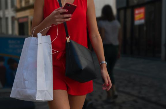 Person in red outfit holding a phone and shopping bags
