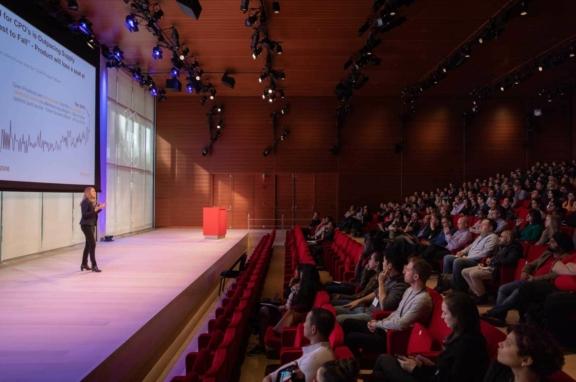Speaker presenting to a large audience in an auditorium