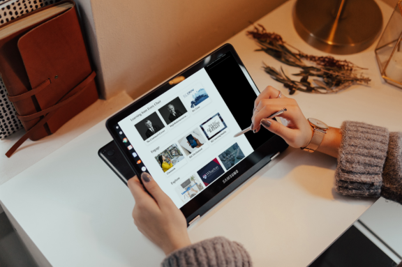 Hands using a stylus on a Samsung tablet displaying a course library