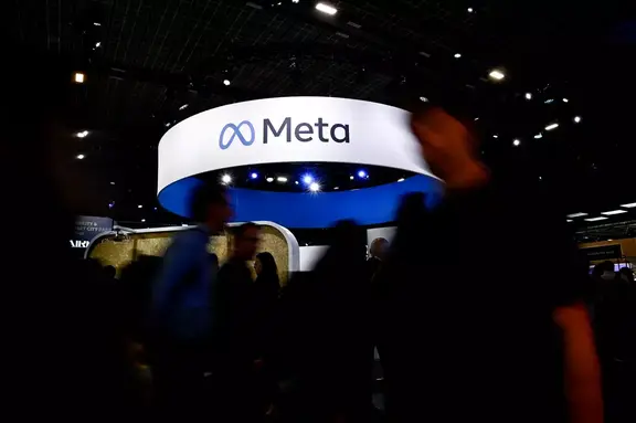 Meta booth sign above a dark conference floor with blurred attendees