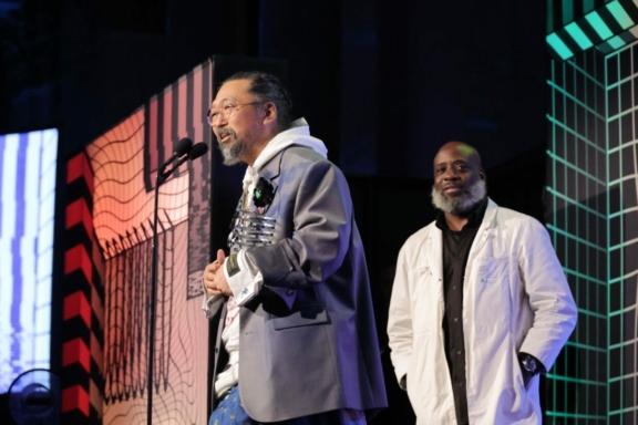 Two speakers on stage with colorful graphic backdrops