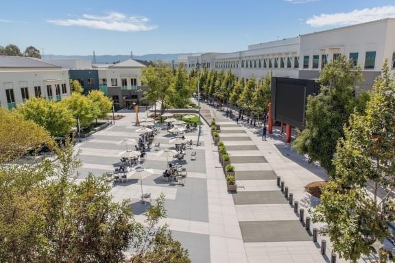 Tree-lined corporate campus courtyard with tables and walkways