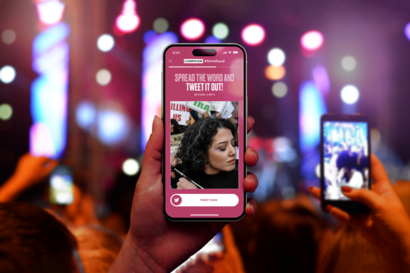 Hand holding a phone with a campaign screen at a concert