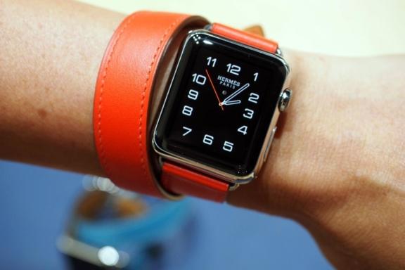 Herms smartwatch with orange strap on a wrist