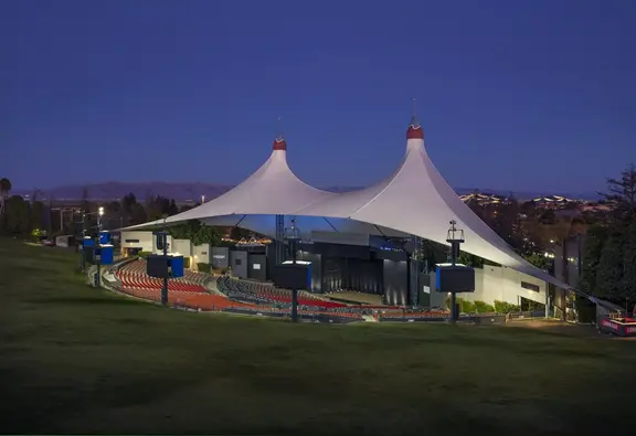 Outdoor amphitheater with white tent-like roof at dusk