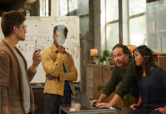 Team meeting around a glass board with notes and diagrams