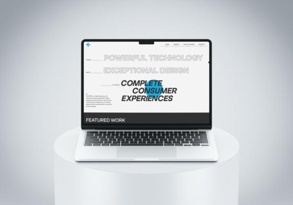 Laptop displaying a design agency website on a white pedestal