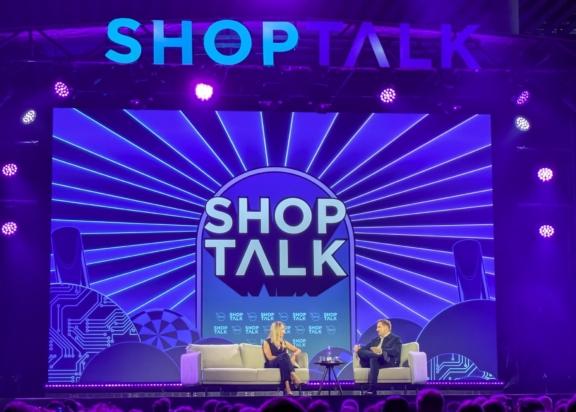 Shoptalk stage with two speakers under blue lighting